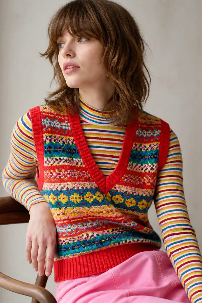 A bright patterned sweater vest worn over a striped top; the colors compete and the outfit looks visually crowded.